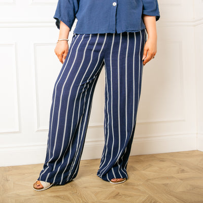The navy blue Pinstripe Linen Trousers with an elasticated waist featuring a drawstring detail